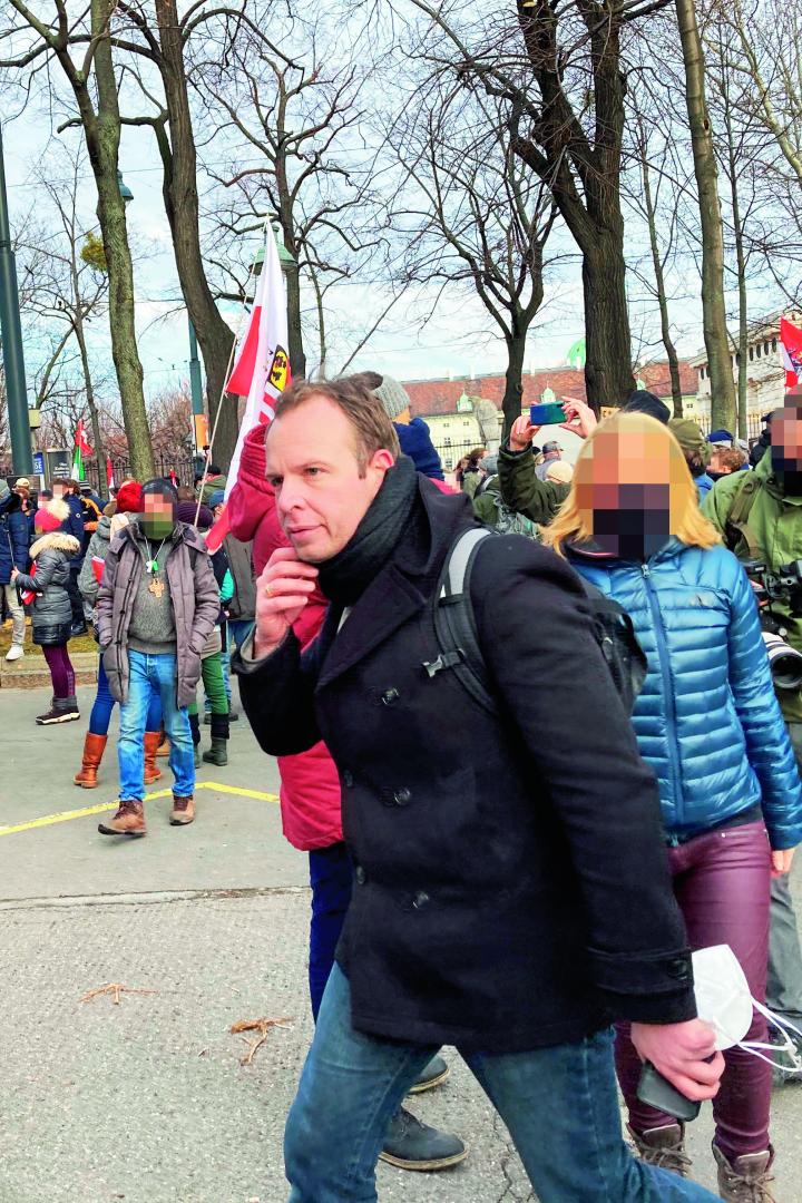 Eine Menschenmenge demonstriert auf einer Straße, im Hintergrund Polizisten.