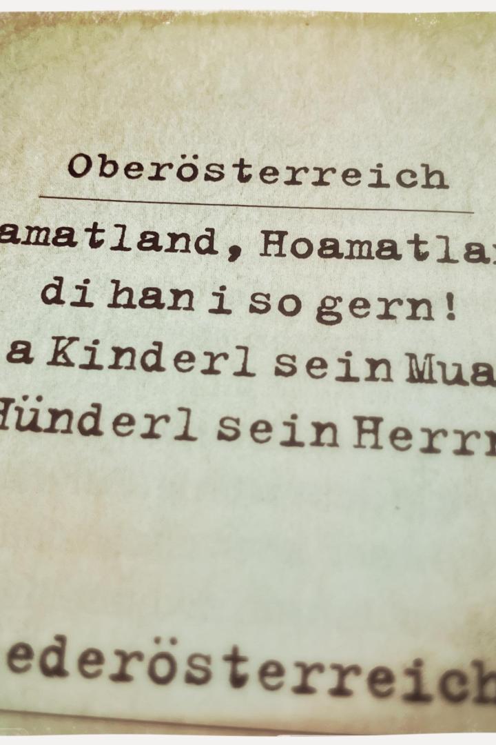 Ein Blatt Papier mit dem Text „Oberösterreich, Hoamatland, Hoamatland, di hani so gern! Viar a Kinderl sein Muader, a Hünderl sein Herrn. Niederösterreich“.