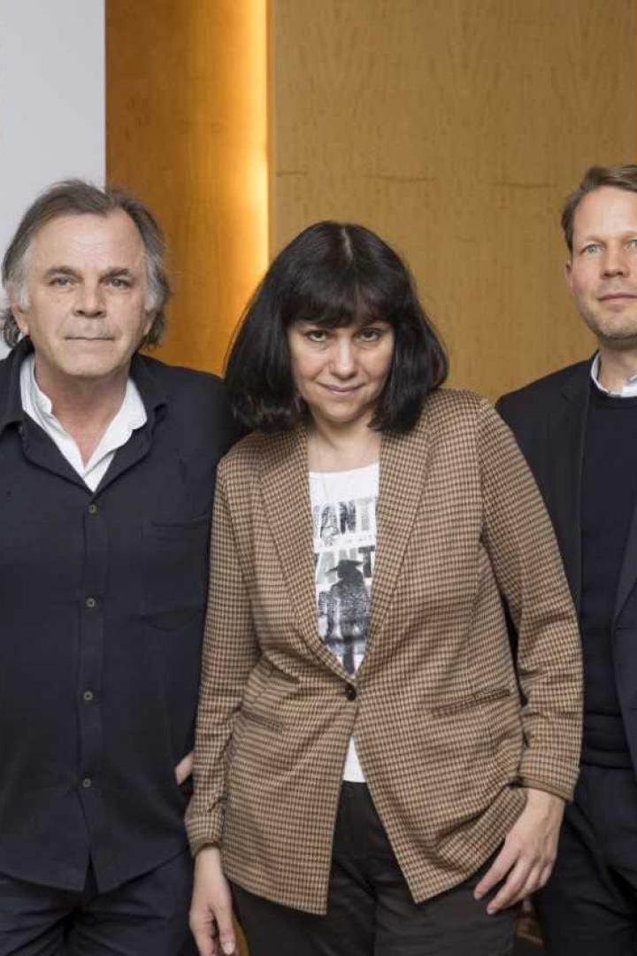 Drei Personen posieren vor einem Plakat der Salzburger Festspiele.
