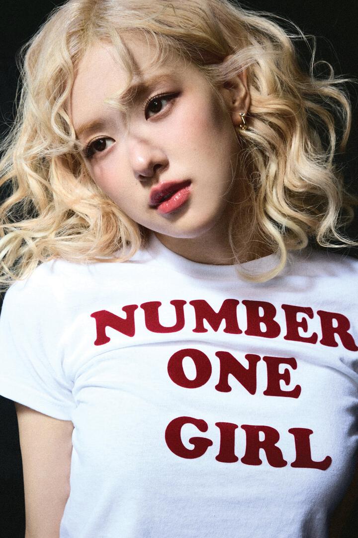 Eine junge Frau mit blonden Locken trägt ein T-Shirt mit der Aufschrift „Number One Girl“.