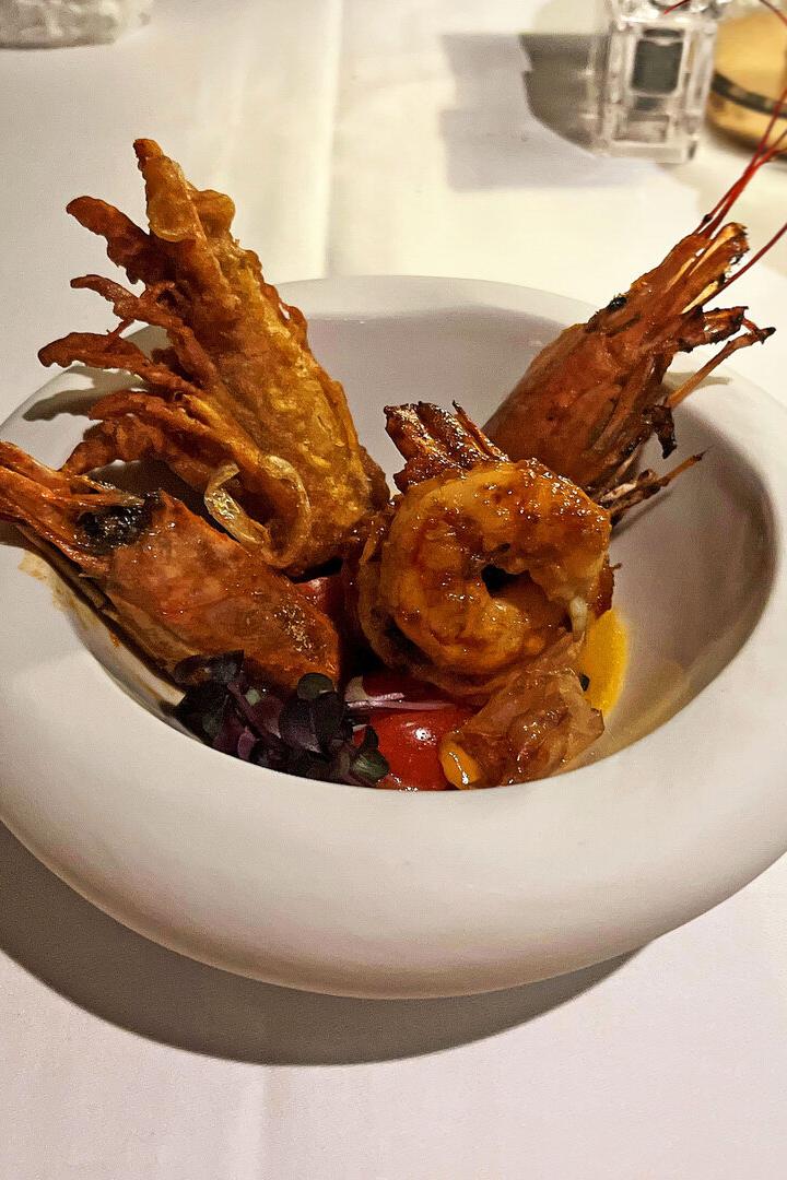 Gegrillte Garnelen werden in einer weißen Schüssel auf einem Tisch serviert.