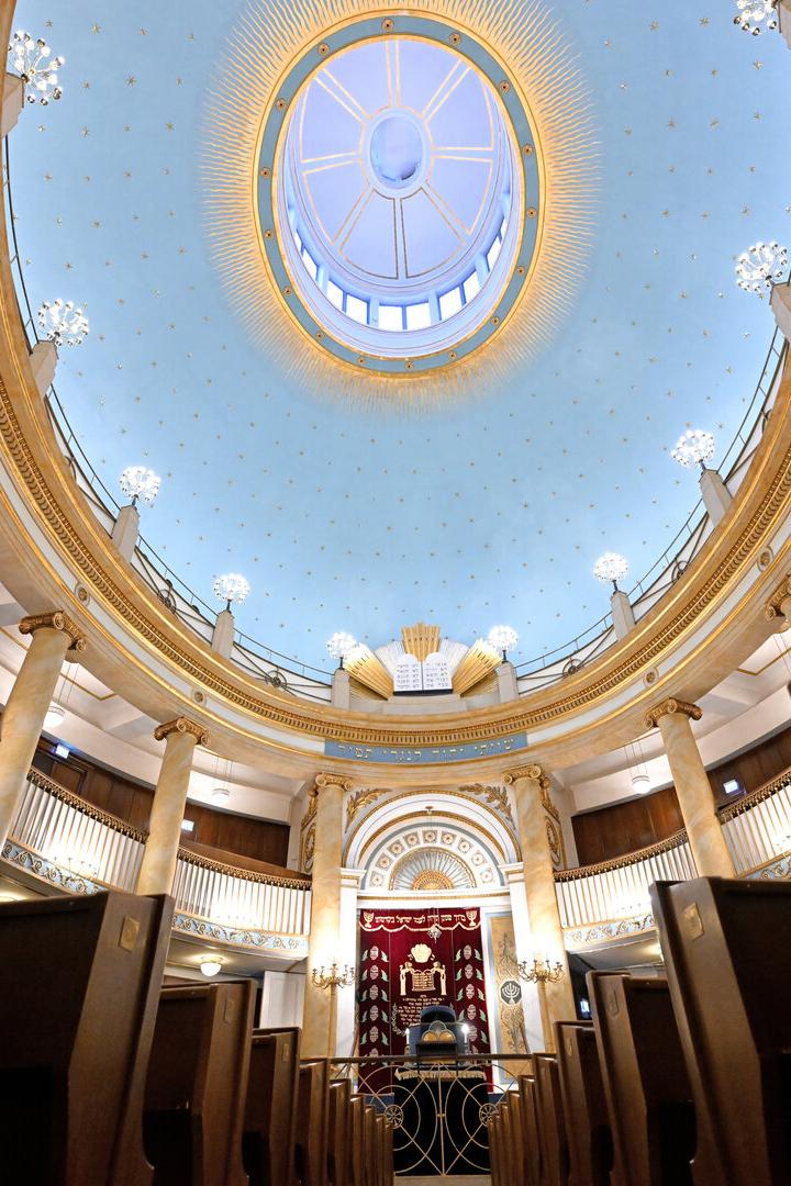 Innenansicht einer Synagoge mit blauer Kuppel und goldenen Verzierungen.