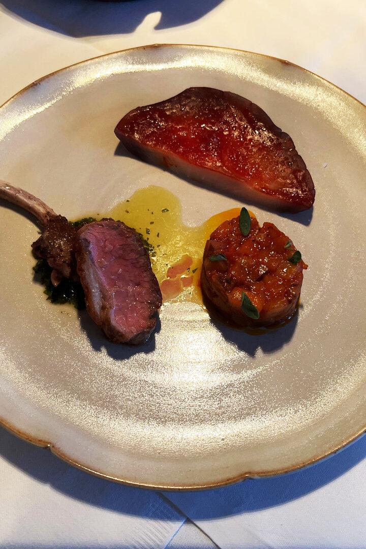 Ein Teller mit Lammkotelett, einem Stück Fleisch und einer Gemüsebeilage.