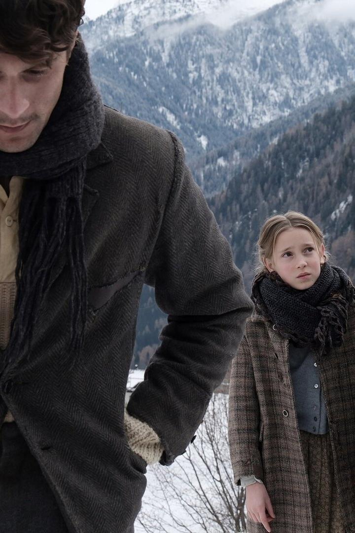 Ein Mann, ein Mädchen und eine Frau stehen in winterlicher Berglandschaft.