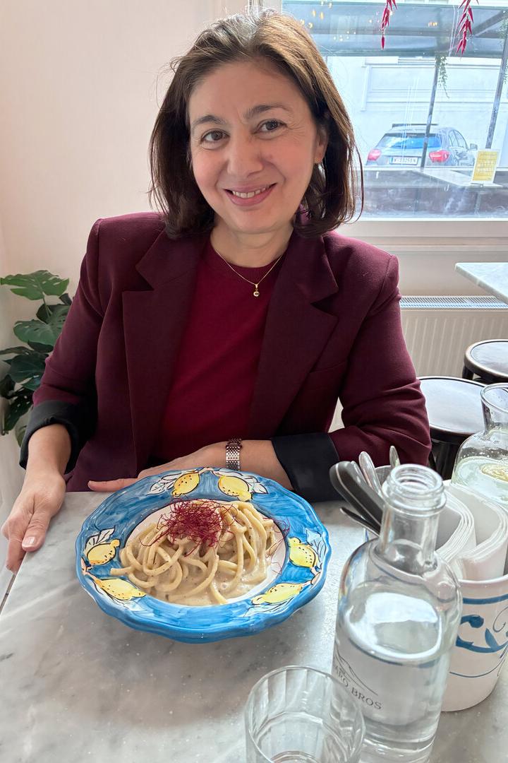 Jetzt-Chefredakteurin Hatice Akyün sitzt an einem Tisch vor einem Teller Spaghetti und lächelt in die Kamera