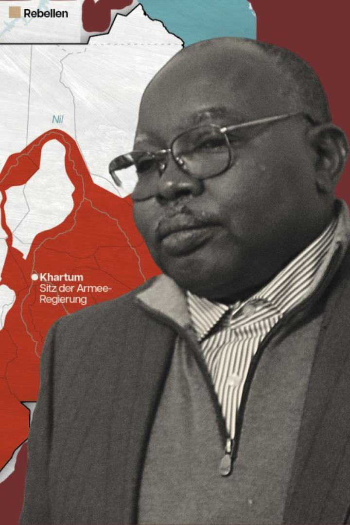 Ein Mann (Abdul Wahid al-Nur) steht vor einer Karte des Sudan.