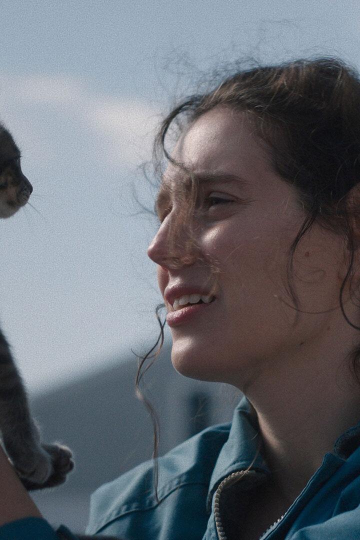 Junge Frau hält Katze hoch und blickt diese fasziniert an.