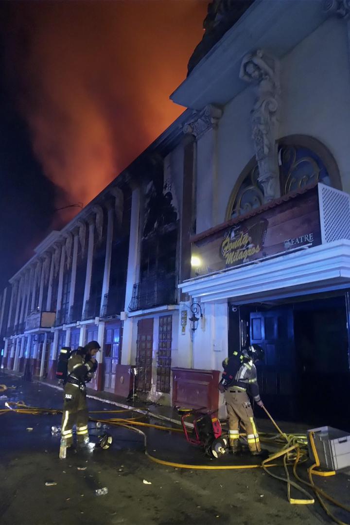 Flammen kommen aus dem Nachtklub, davor Feuerwehrleute mit Schläuchen