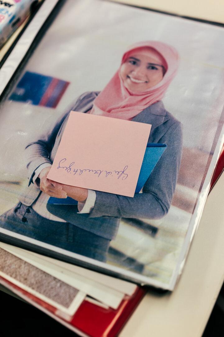 Frau mit Kopftuch trägt eine Mappe