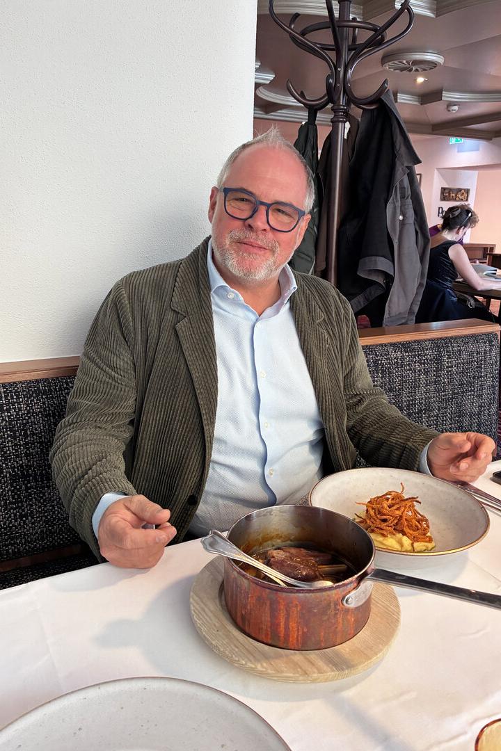 Hotelier Wolfgang Gröller sitzt an einem Wirtshaustisch, vor sich ein Kupferkessel und ein Teller mit Kartoffelpüree