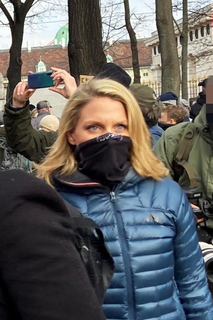 Maskierte Frau in blauer Jacke auf einer Corona-Demo mit Maskenpflicht