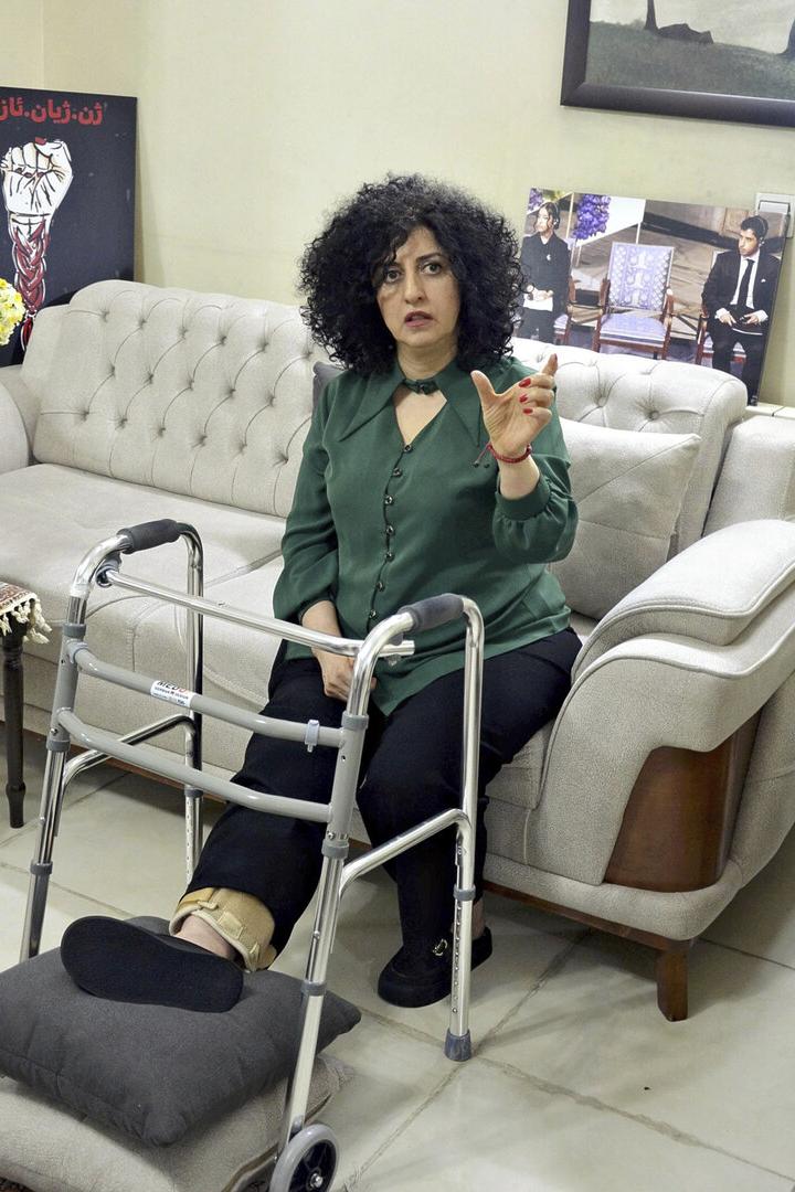 Eine Frau sitzt auf einem Sofa, ihr Bein ist verletzt