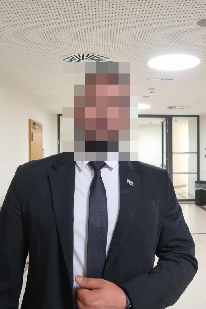 Zeuge Achmad in Anzug in einem Gang des Wiener Landesgericht, sein Gesicht ist verpixelt.