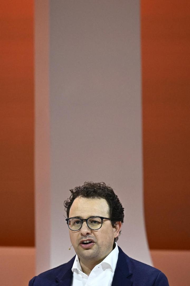 Dario Amodei spricht auf einer Bühne vor orangefarbenem Hintergrund.