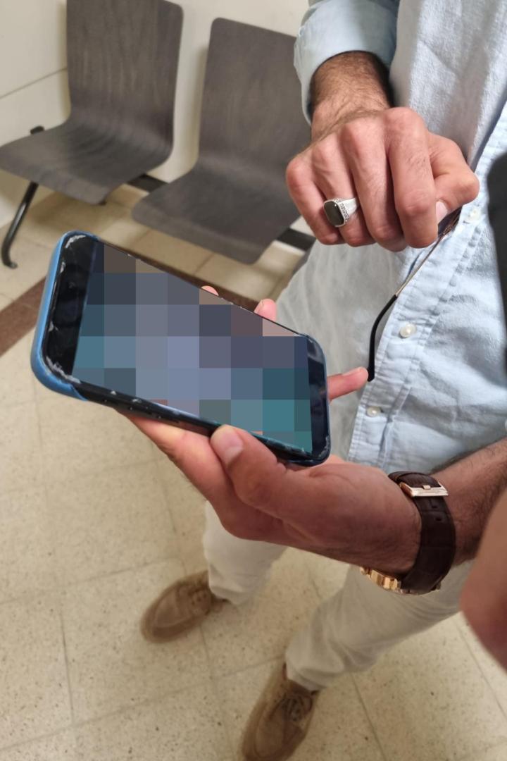 Der Zeuge hält ein Handy in der Hand. Der Bildschirm ist verpixelt.
