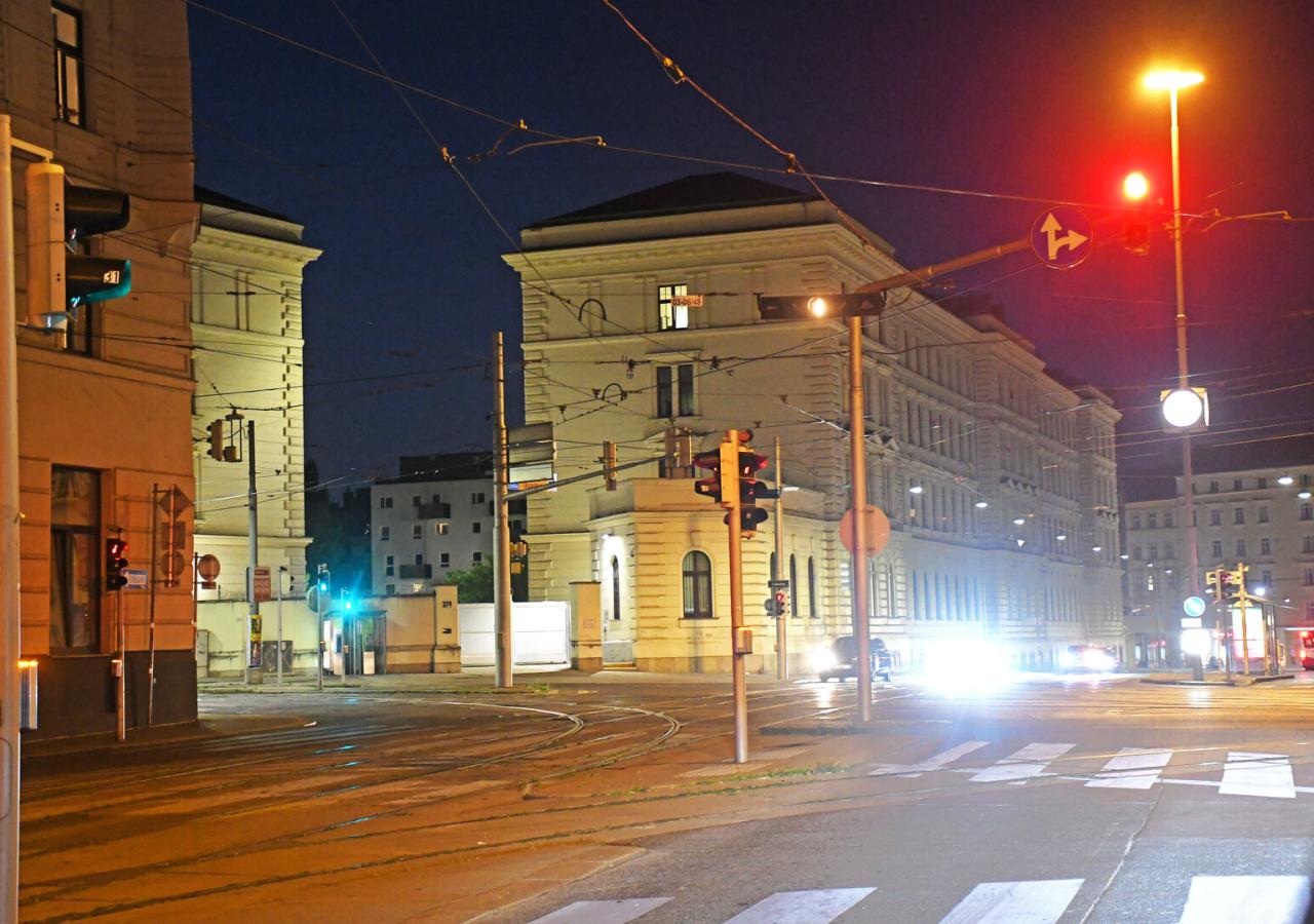 Eine nächtliche Straßenszene in einer Stadt mit beleuchteten Gebäuden und Ampeln.