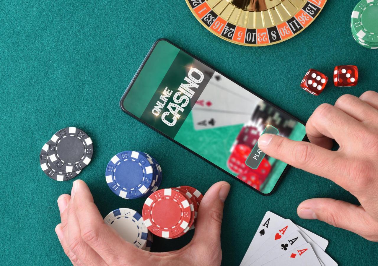 Ein Smartphone zeigt ein Online-Casino, umgeben von Spielchips, Würfeln und einem Vierling Asse.