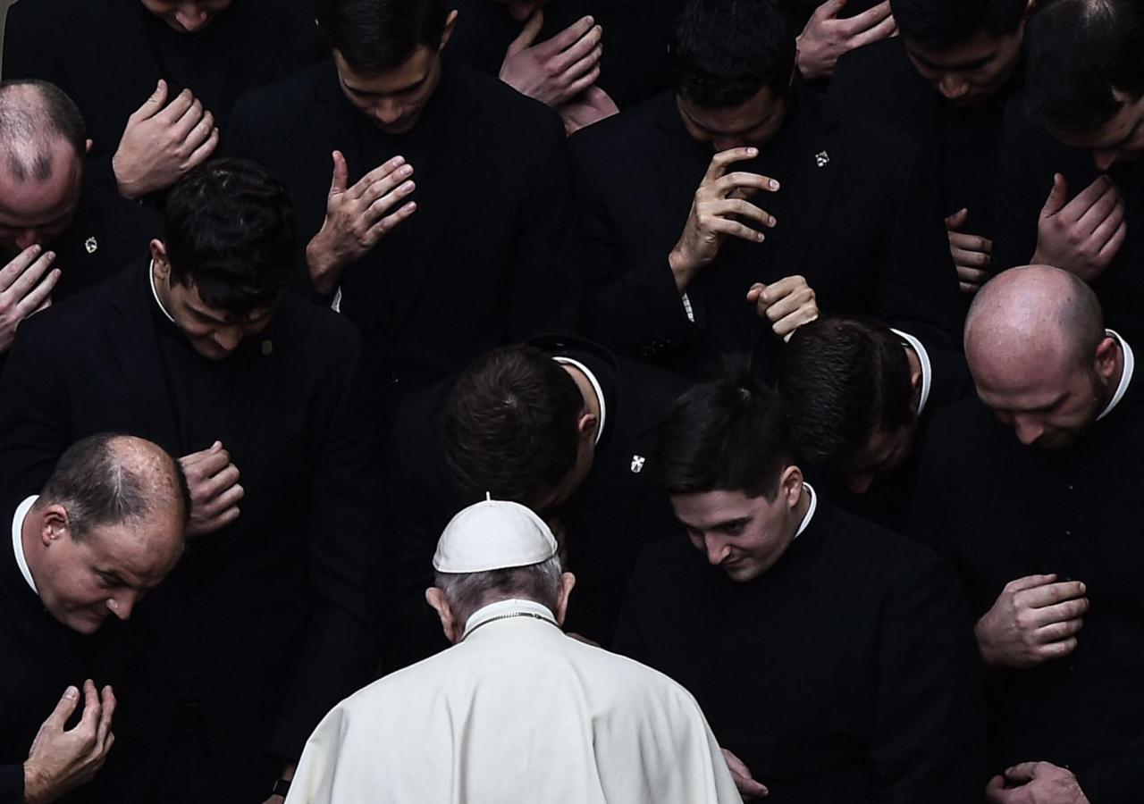 Papst Franziskus umgeben von einer Gruppe Priester.