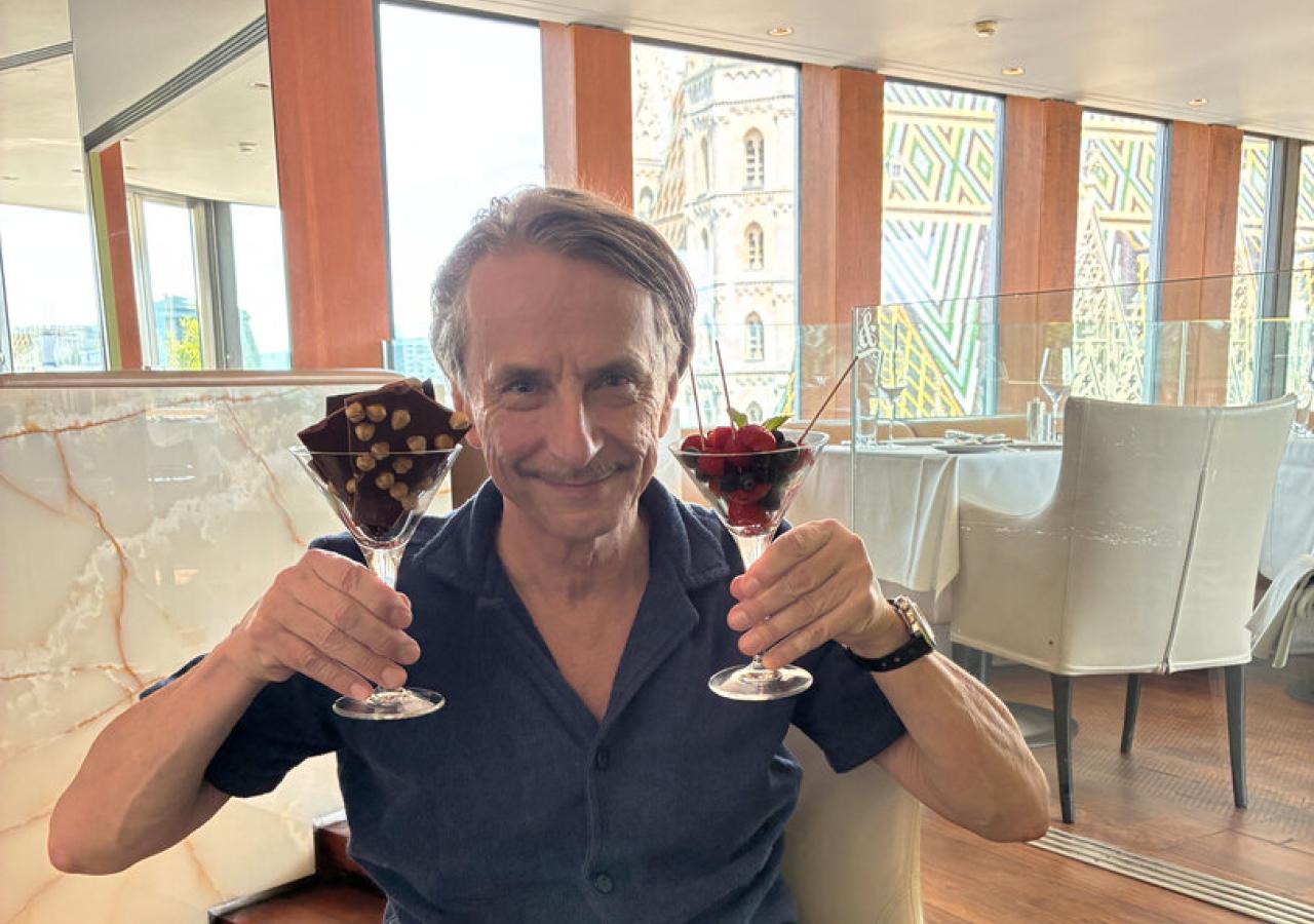 Ein Mann hält zwei Martinigläser mit Schokoladenstückchen und Beeren in einem Restaurant.