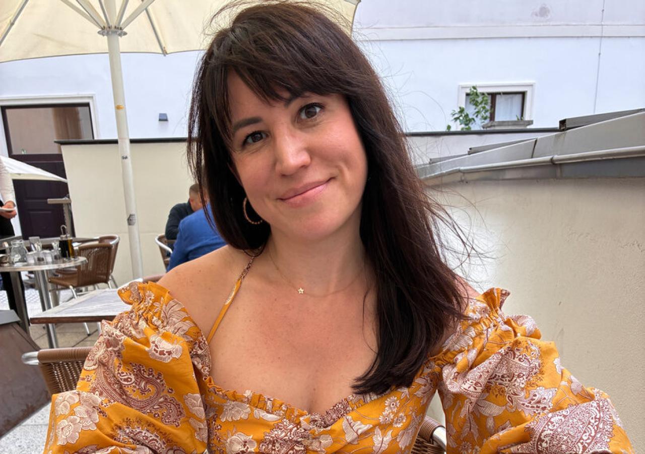 Eine Frau sitzt an einem Tisch mit Speiseresten und einem leeren Teller.