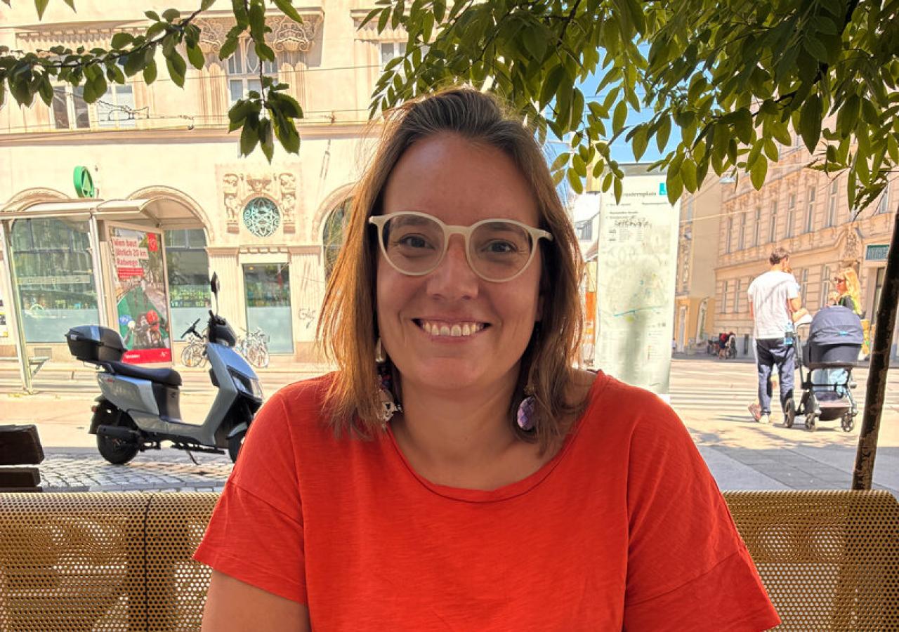 Eine Frau lächelt an einem Tisch mit Salat und einem Teller mit Speisen in einem Restaurant.