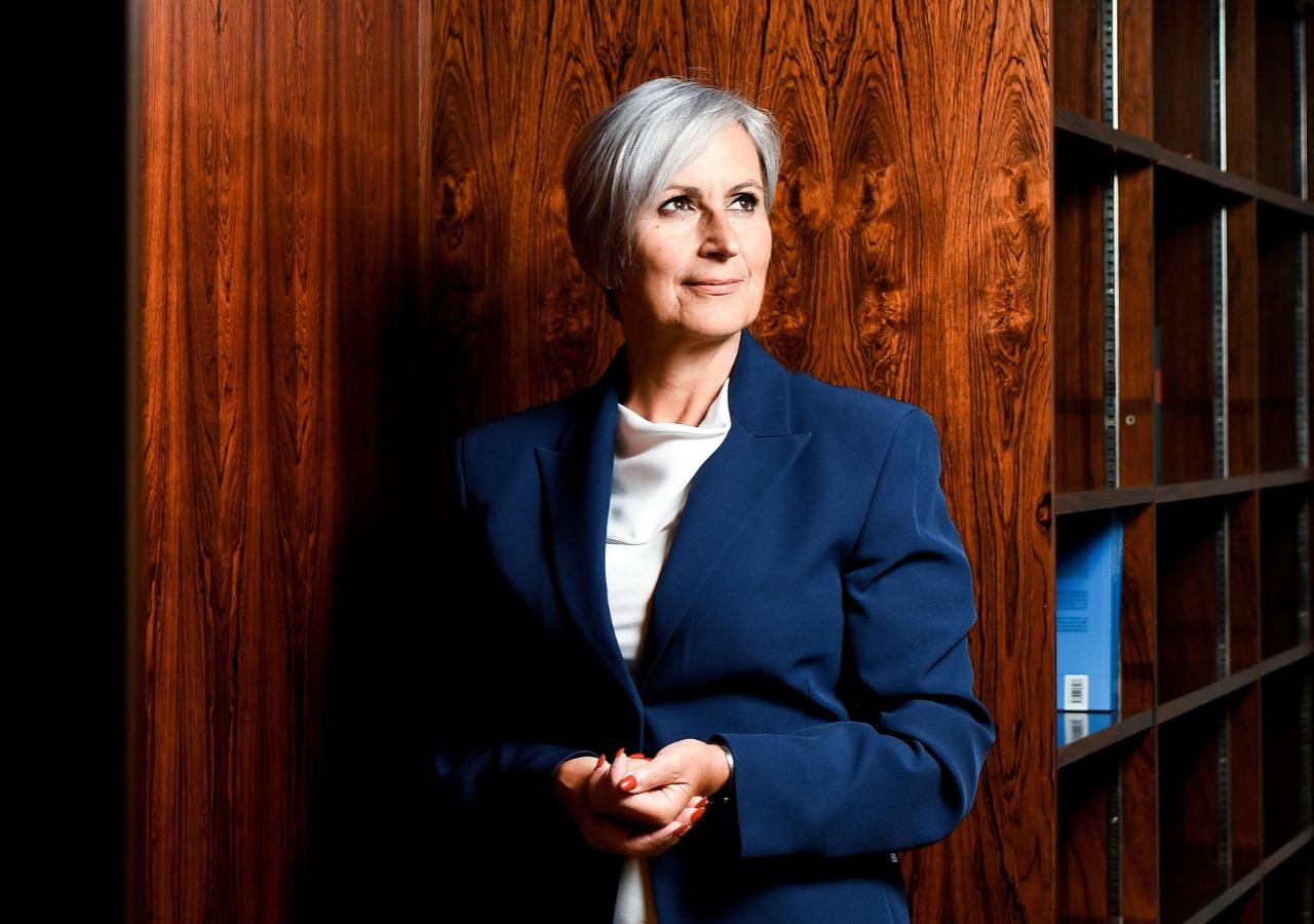 Anna Sporrer steht vor einer Holzwand in ihrem Büro 