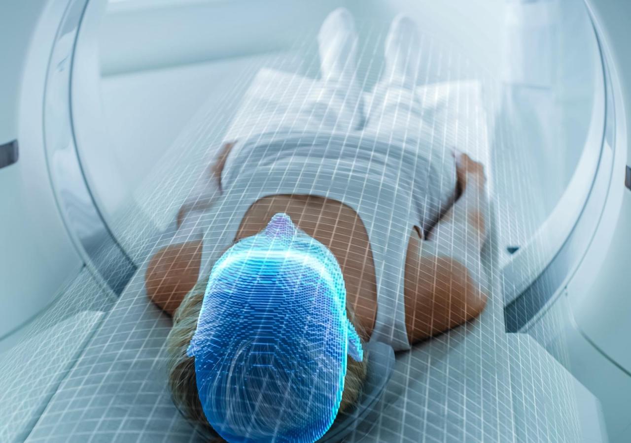 Eine Person liegt in einem Magnetresonanztomografen, wobei die Hirnaktivität aufgezeichnet wird.