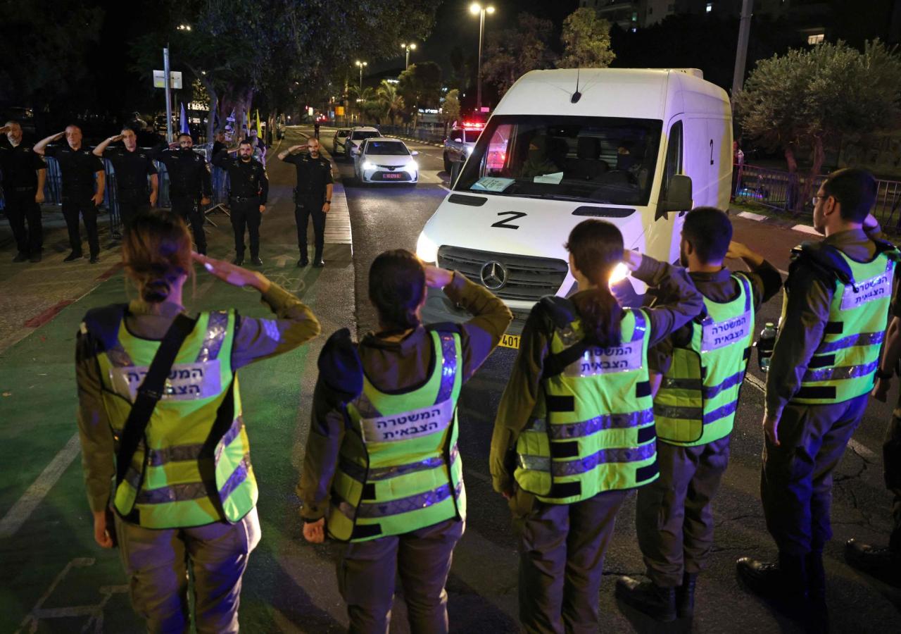 Ein Kleinbus, davor stehen Menschen in Warnwesten und salutieren