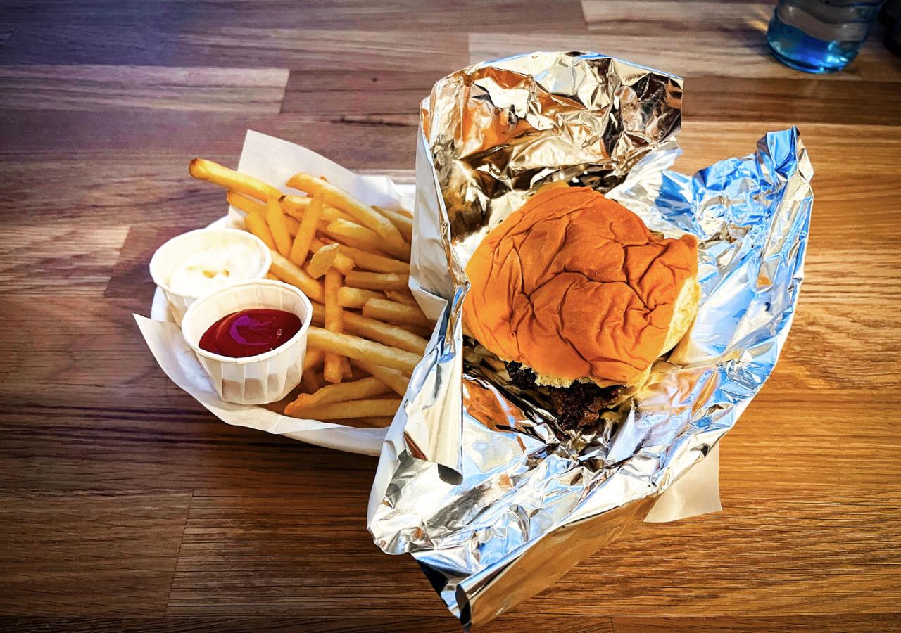 Das Bild zeigt einen Smashburger mit Pommes, Ketchup und Mayonnaise