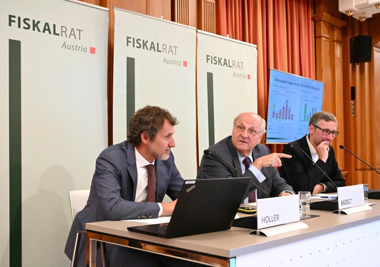 Die Vertreter des Fiskalrats, in der Mitte Präsident des Fiskalrates Christoph Badelt, sitzen nebeneinander bei der Pressekonferenz. Hinter ihnen sind drei Banner mit dem Fiskalrats-Logo.