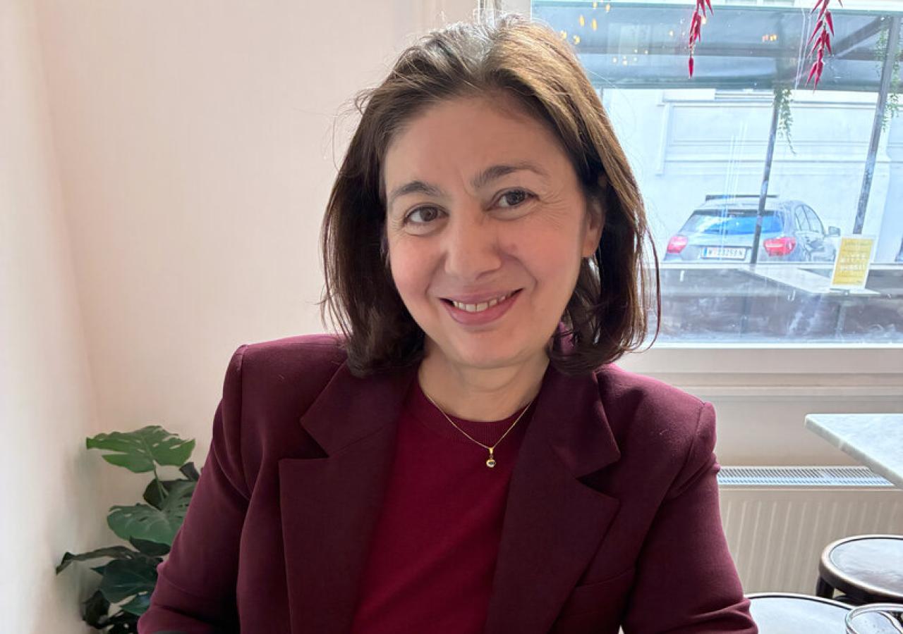 Jetzt-Chefredakteurin Hatice Akyün sitzt an einem Tisch vor einem Teller Spaghetti und lächelt in die Kamera