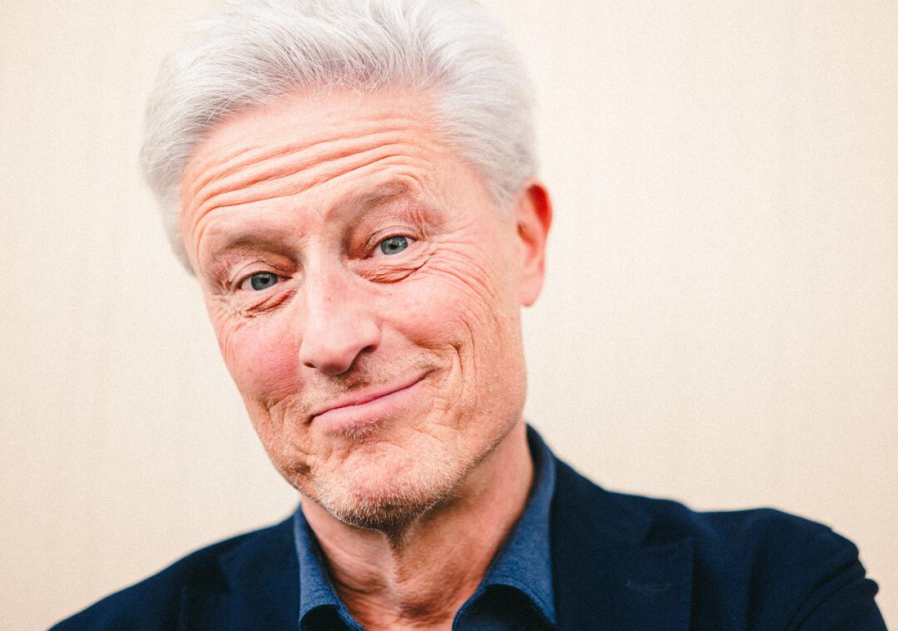 Kabarettist Florian Scheuba, in Hemd und Sakko, lächelt in die Kamera