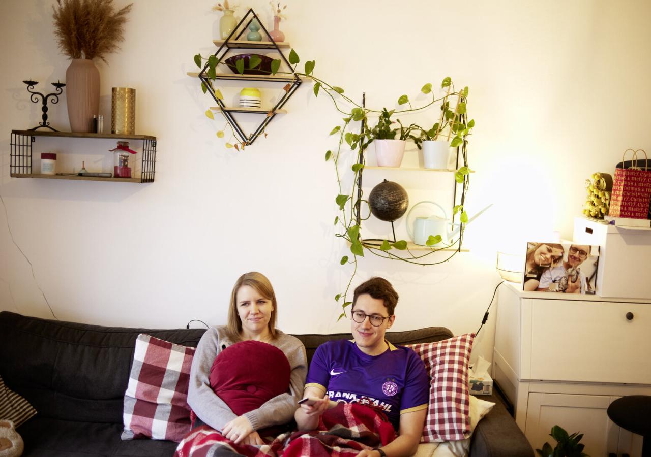 Long-Covid-Betroffene Dini und Lukas auf der Couch im Wohnzimmer