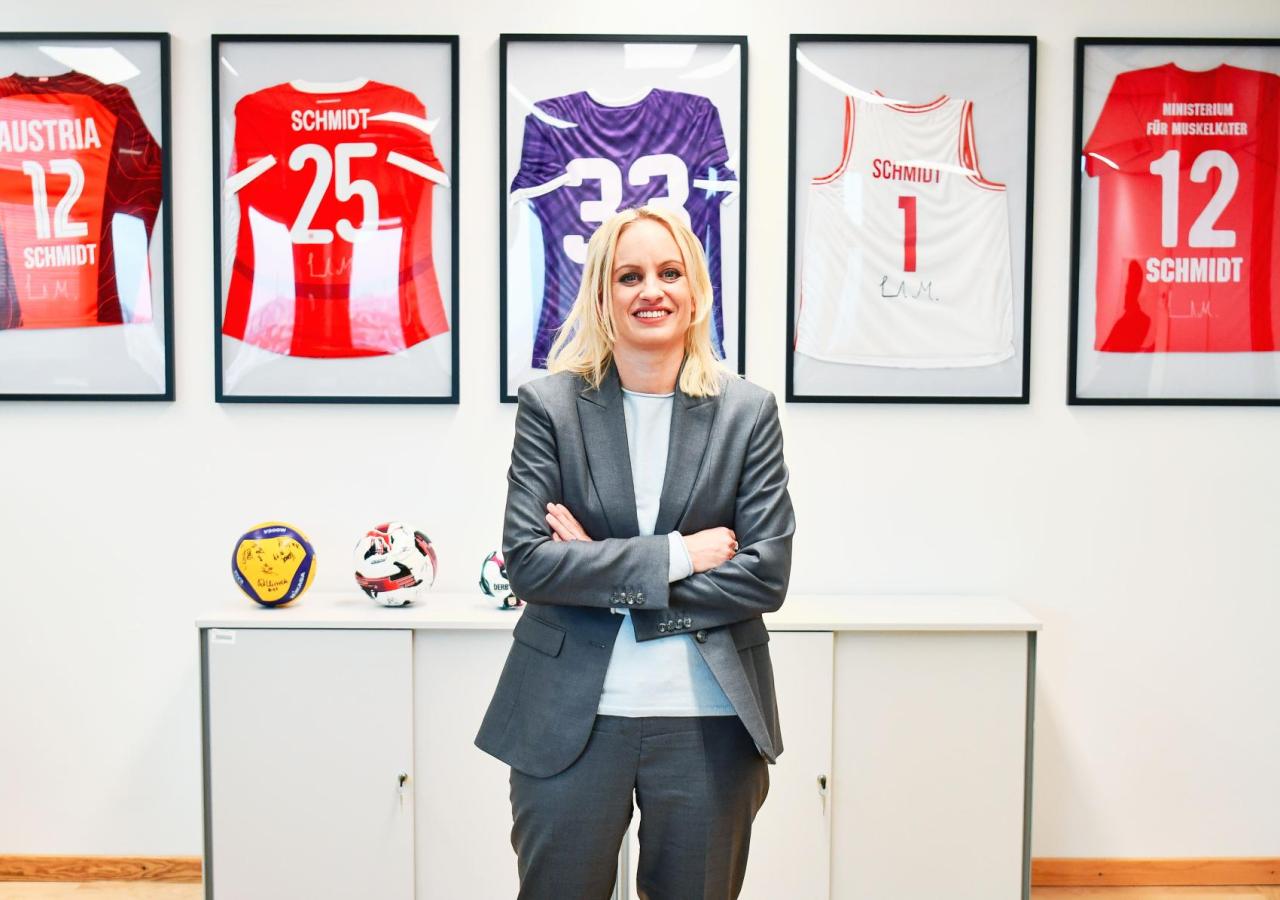 Staatssekretärin Michaela Schmidt und Regierungskoordinatorin steht vor einer Wand mit Sporttrikots