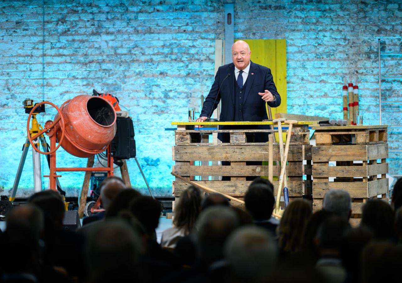 Ein Mann, es ist Bundeskanzler Stocker, steht auf einer Bühne und spricht.