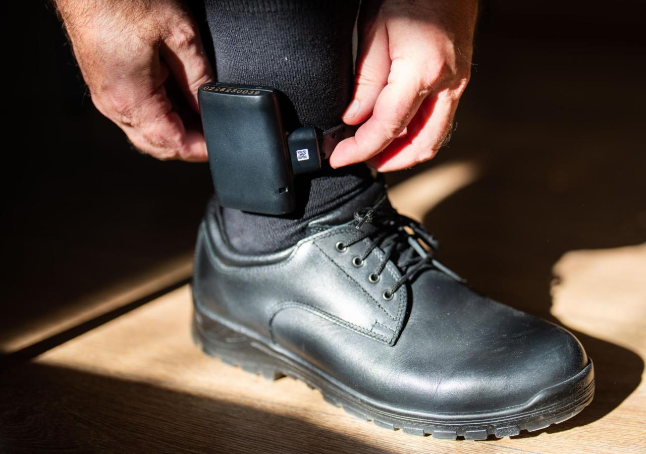 Mann richtet seine Fußfessel am Bein