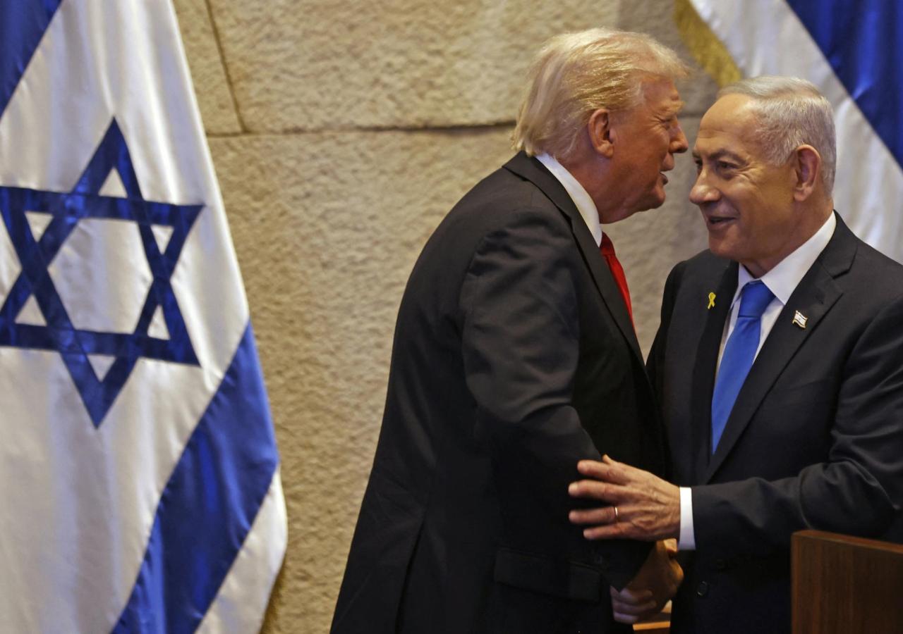 Trump spricht Netanjahu etwas ins Ohr, links eine Israel-Flagge.