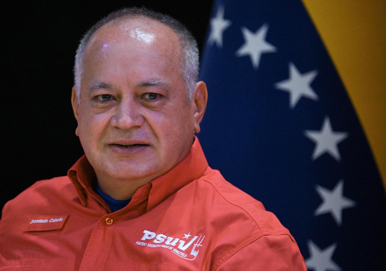 Cabello steht vor einer Venezuela-Flagge, auf seinem roten Hemd liest man "PSUV".