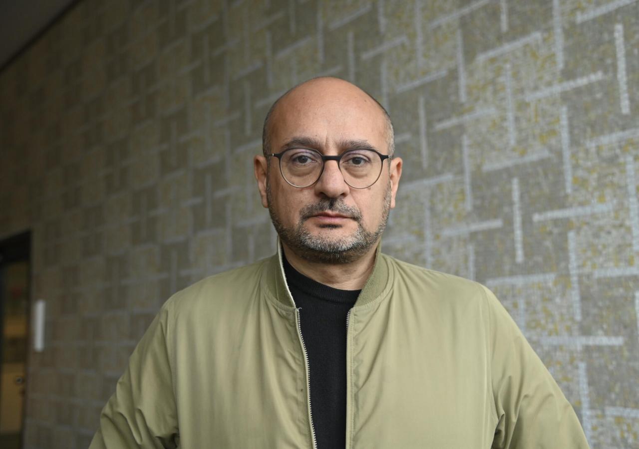 Arash T. Riahi steht vor einer Wand.