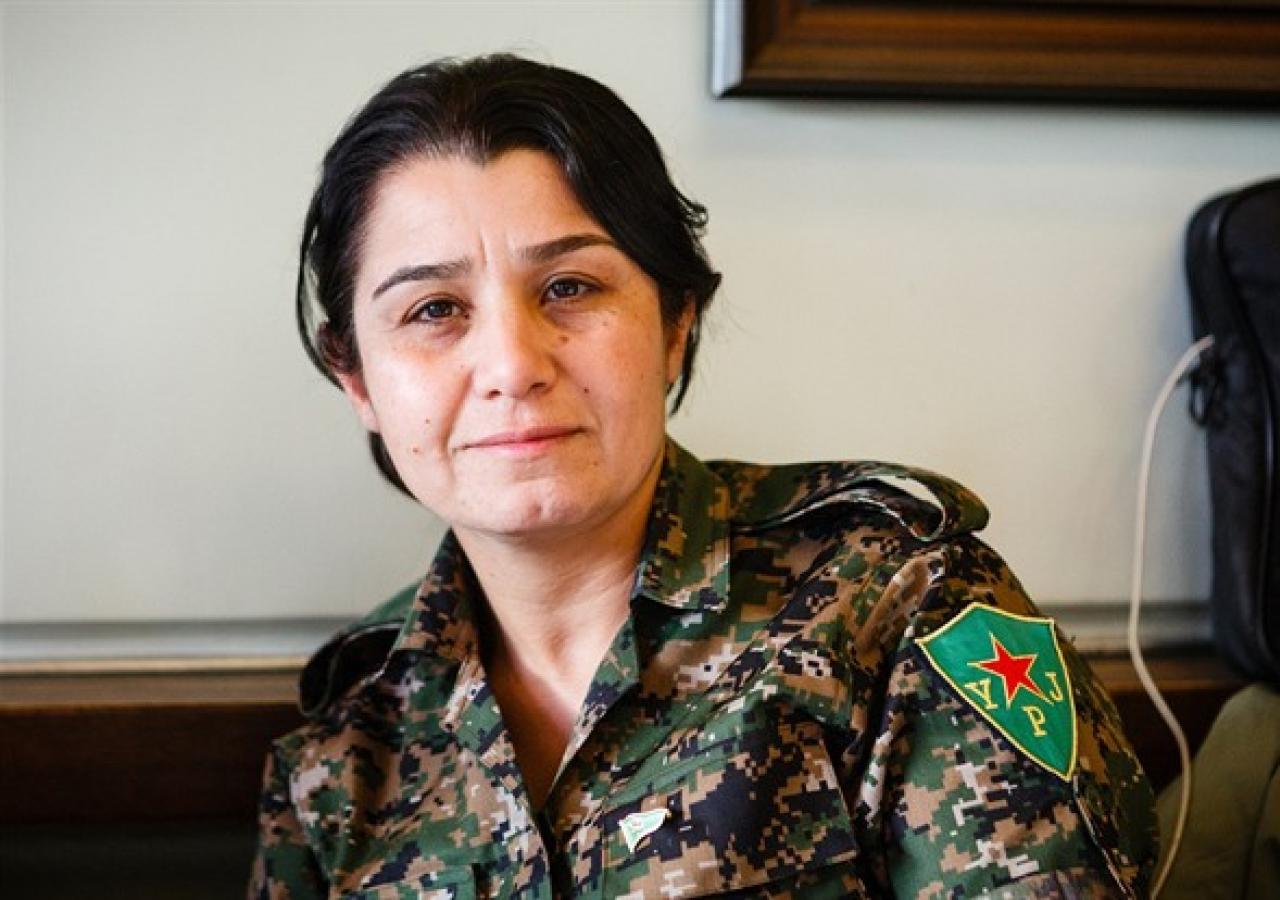Nesrin Abdullah in Tarnkleidung, sie trägt am Arm einen Aufnäher mit der Aufschrift "YPJ" und einem roten Stern.