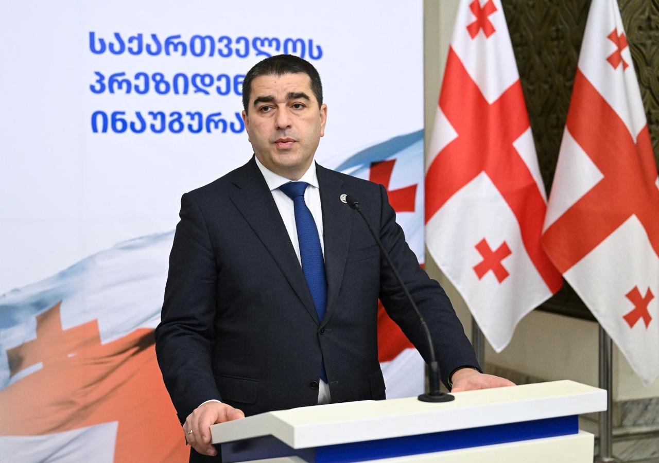 Shalva Papuashvili steht vor einem Redepult, rechts Georgien-Flaggen.