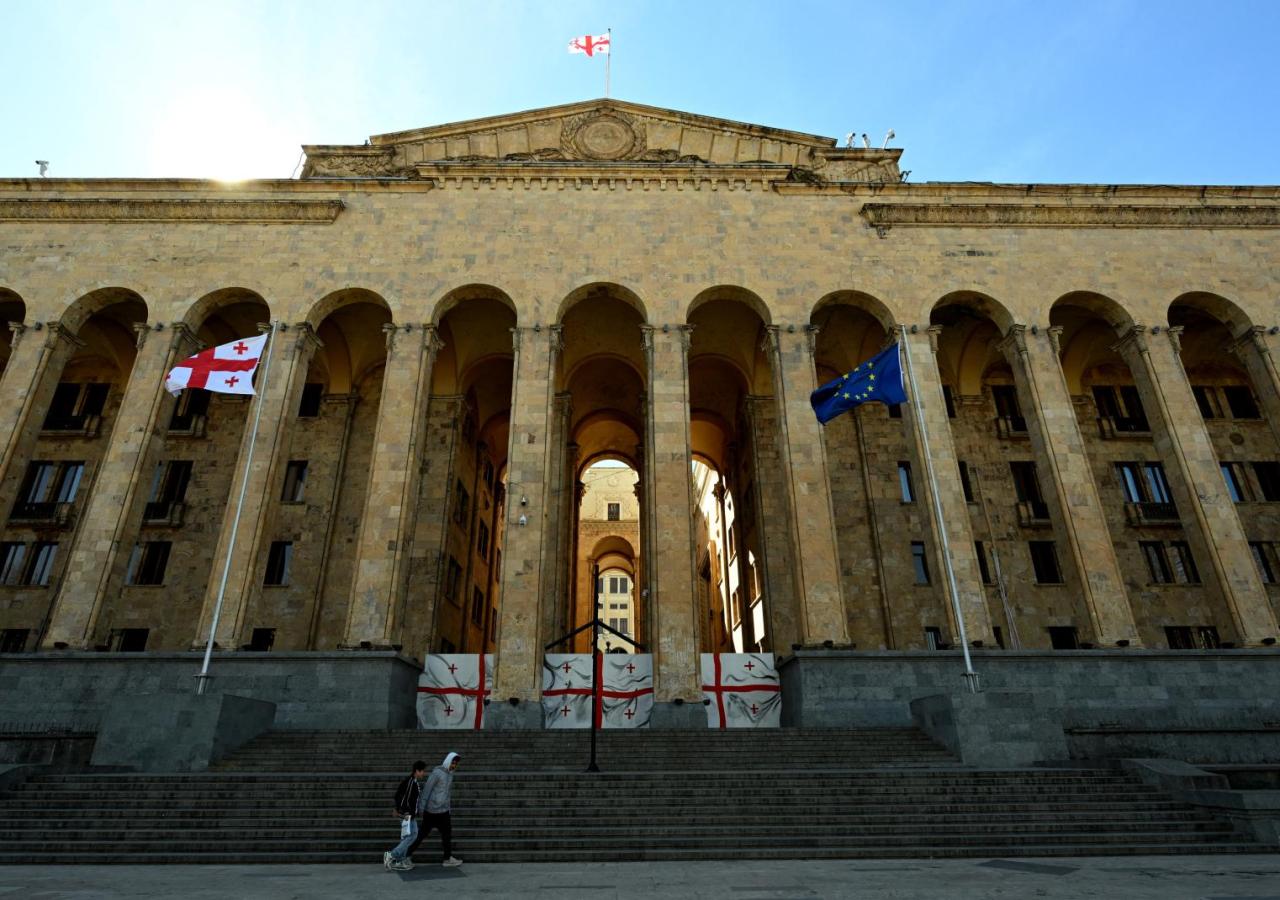 Frontalfoto von Georgiens Parlament, es ist ein großes Gebäude aus hellem Vulkanstein mit griechischen Säulen.