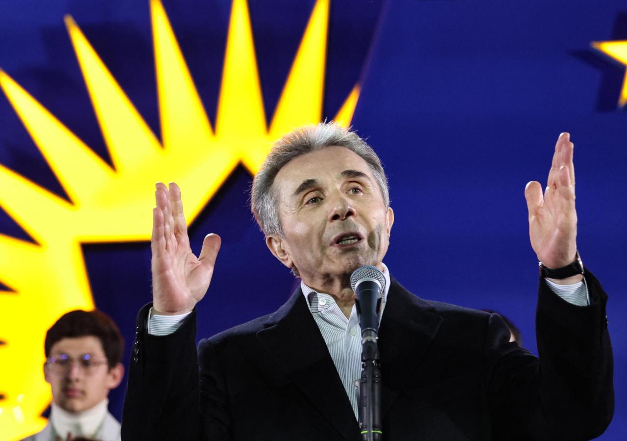 Bidsina Iwanischwili haltet eine Rede, dahinter das Parteilogo des Georgischen Traum.