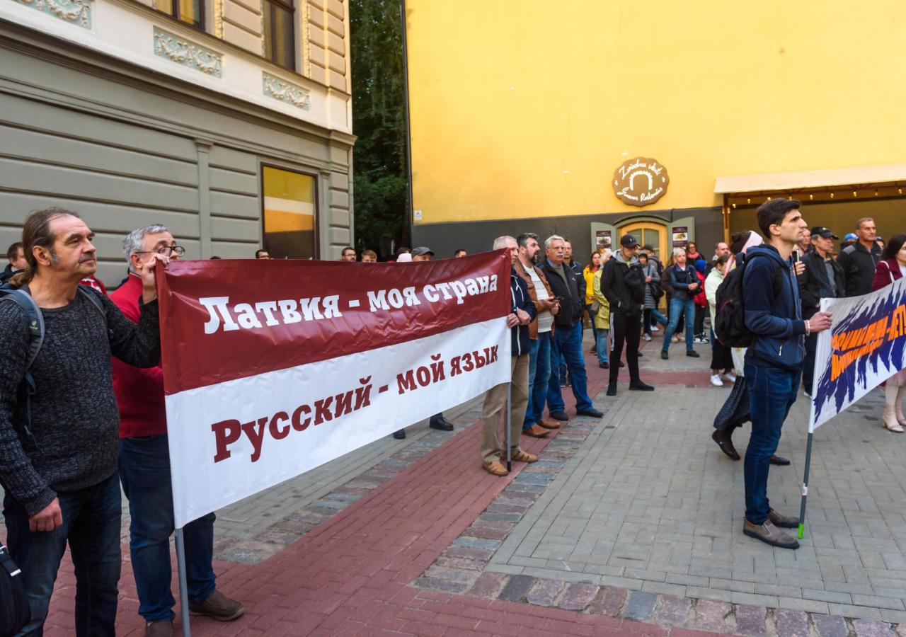 Protestierende halten ein Plakat hoch - darauf steht Latvija moja strana - russkij moj jazik (Lettland ist mein Land - Russisch meine Sprache).