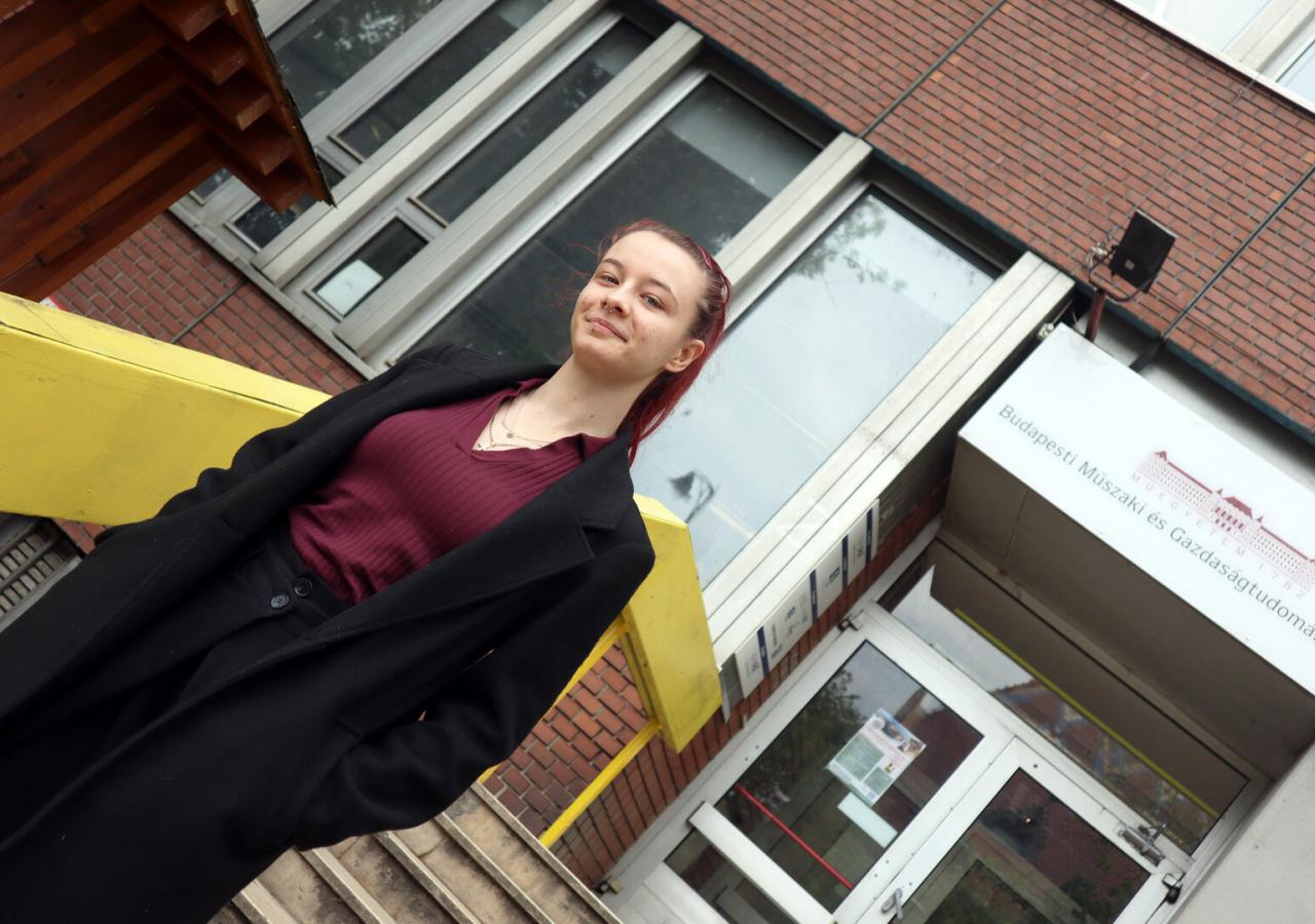Studentin Dorka steht auf der Treppe ihrer Uni.