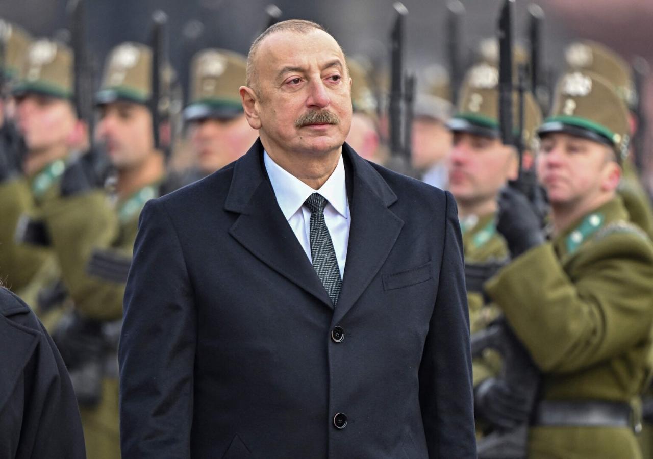 Ilham Aliyev in Anzug vor Soldaten