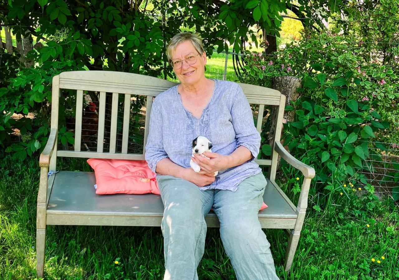 Andrea Tews mit Hundewelpen auf einer Gartenbank im Grünen