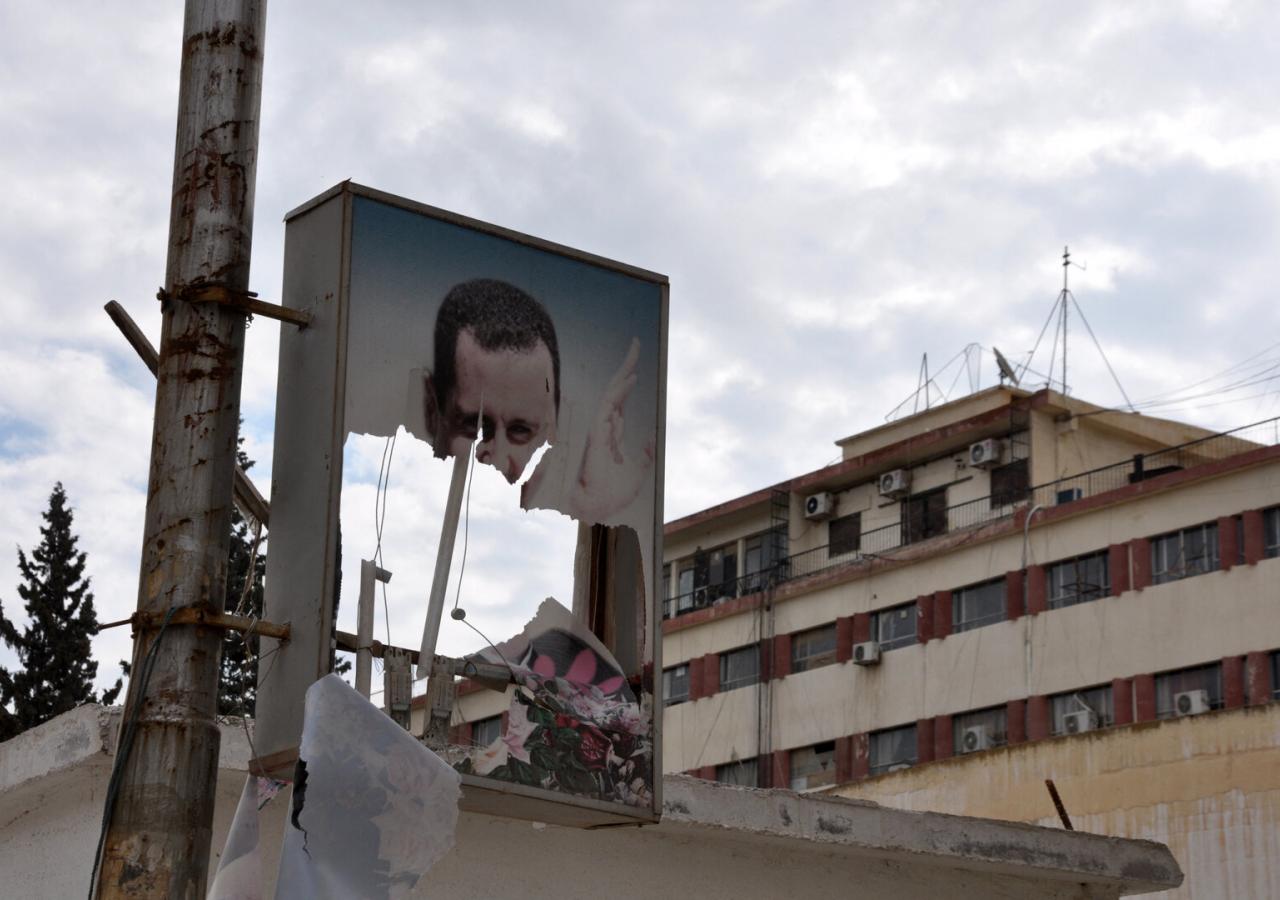 Ein zerschlissenes Assad-Poster vor einem Haus in Rakka.
