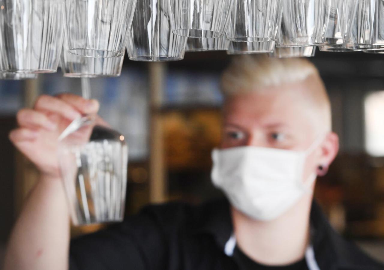 Barkeeper mit Maske hinter Weinkläsern