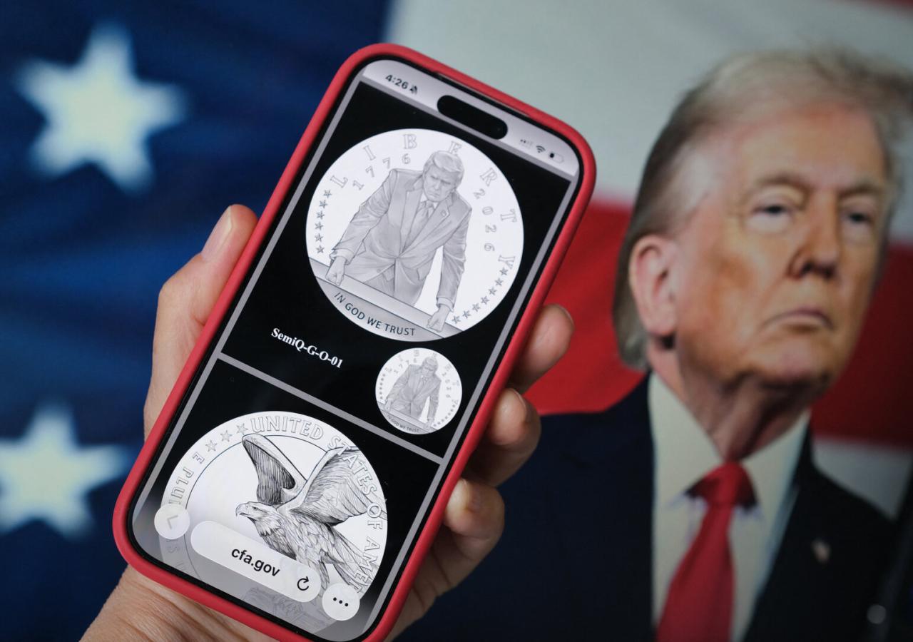 Auf einem Handy sieht man eine Münze mit Donald Trump darauf.